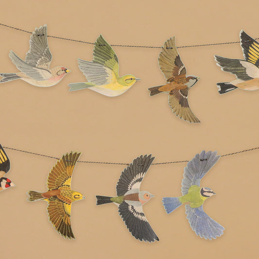 Decorations of various birds hanging on a string garland on a beige background