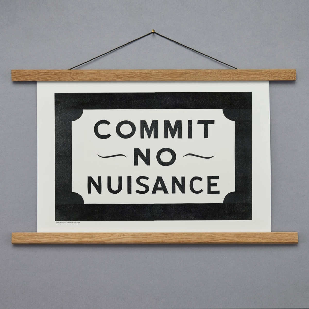 Hanging print with 'Commit No Nuisance' text on a gray background