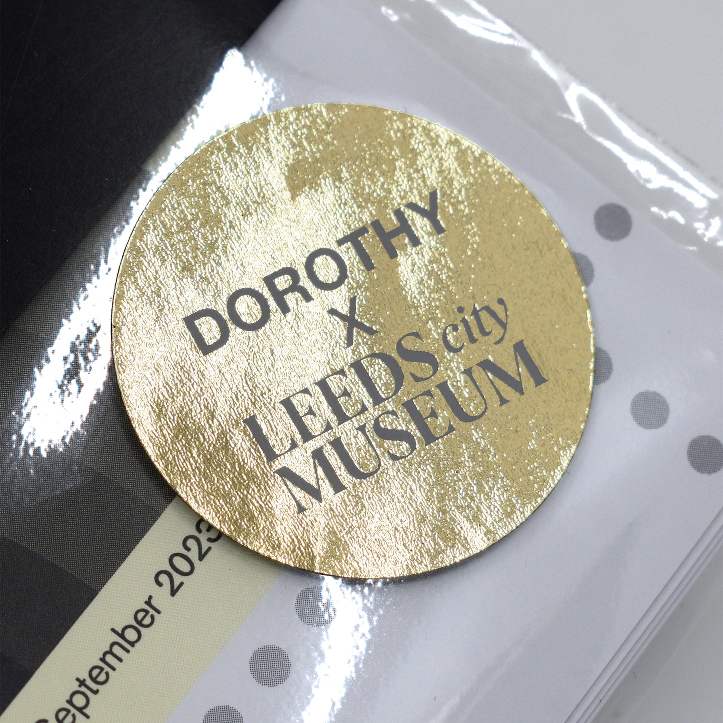 Gold circular label with 'DOROTHY x LEEDS city MUSEUM' text on a white background.