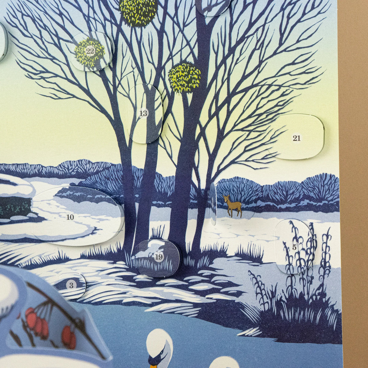A winter landscape advent calendar featuring illustrated bare trees, snow, hills, and numbered door cutouts.