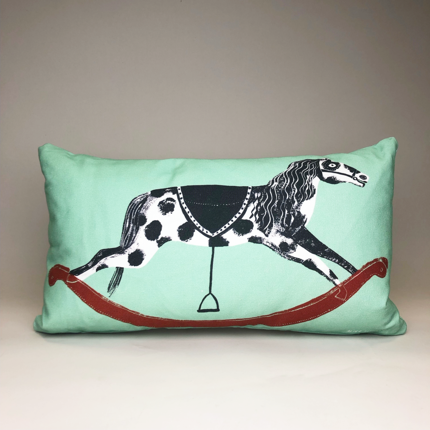 A green rectangular cushion with a victorian rocking horse design for Abbey House Museum