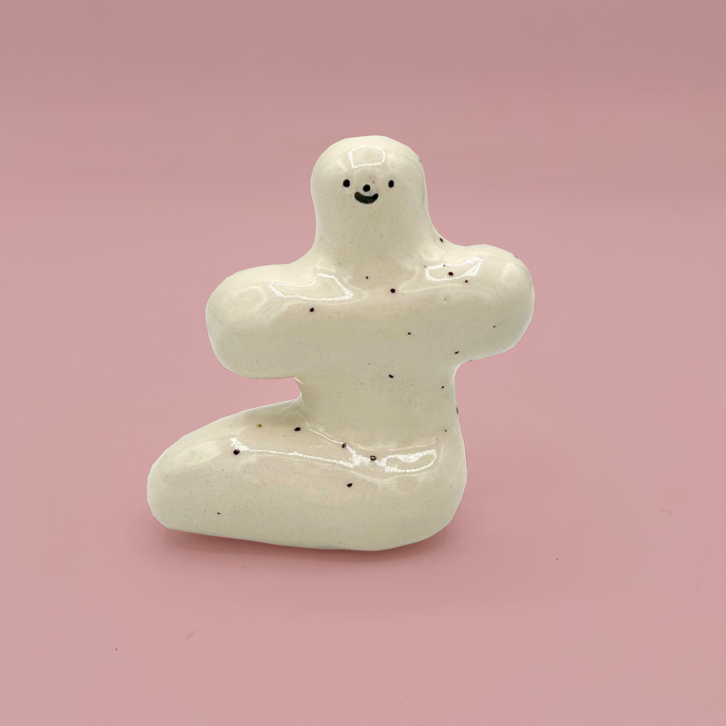 White ceramic figure with a smiling face on a pink background