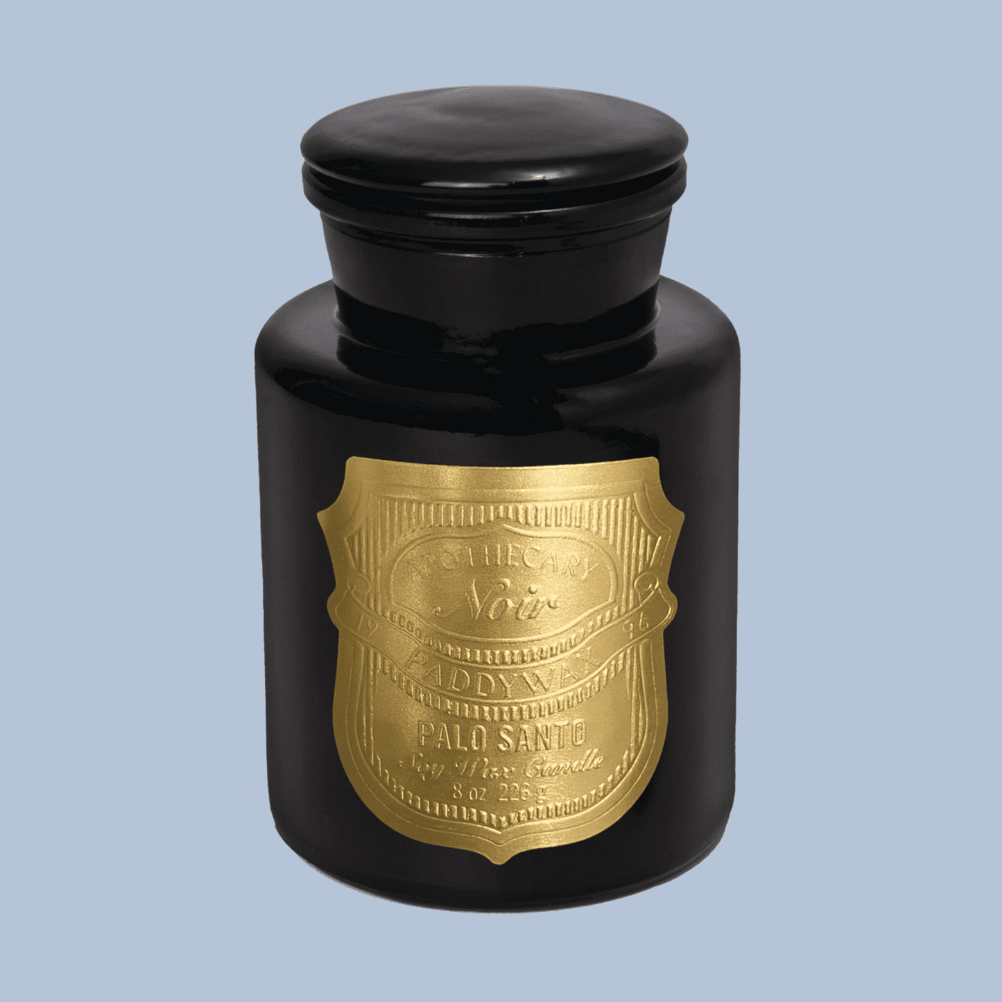 Black candle jar with gold label on a light blue background