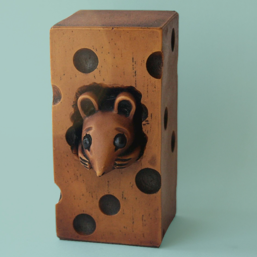 Carved figurine of a mouse inside a block of cheese.