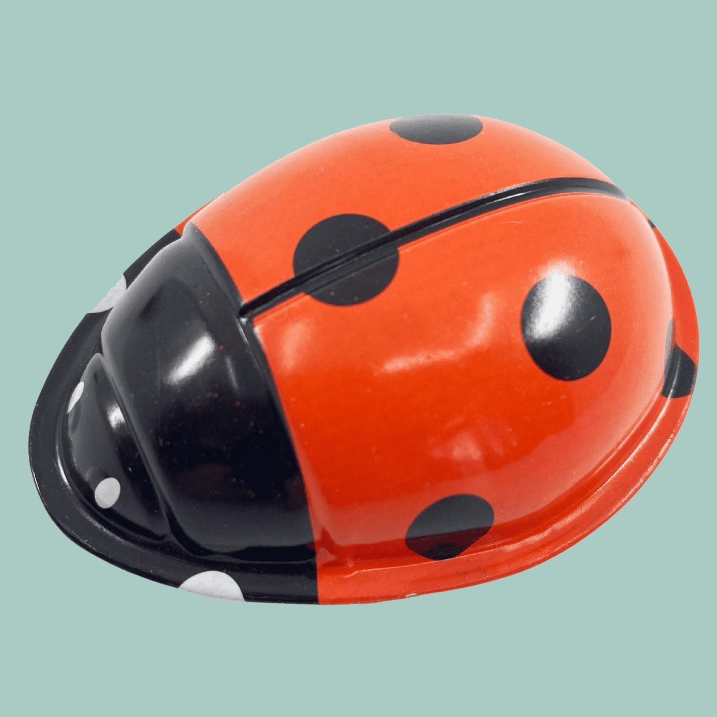 Red and black ladybug-shaped object on a light blue background