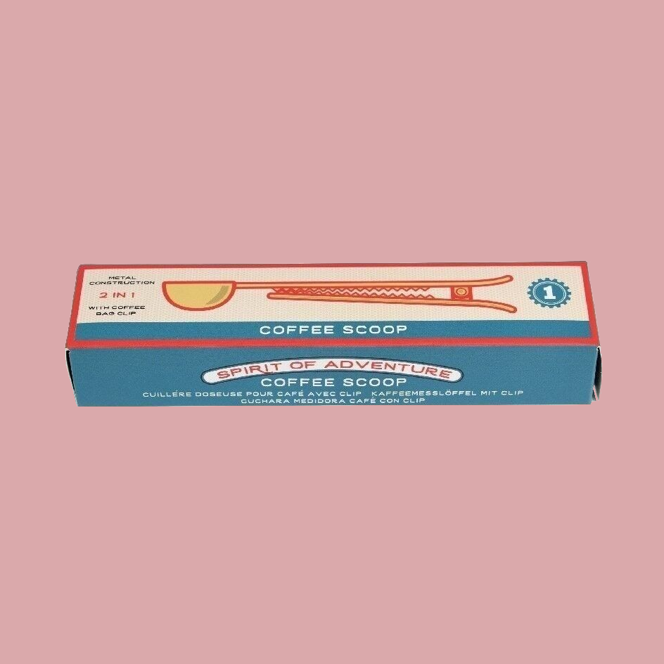 A retro-style coffee scoop kit box with a blue and cream design, featuring an illustration of the included scoop and coffee cup, set against a solid dusty pink background.