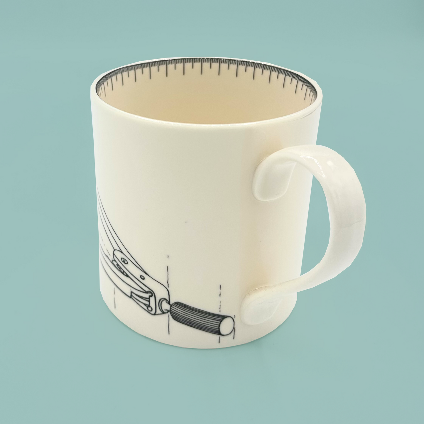 White mug with a design of a compass and a curved handle on a light blue background