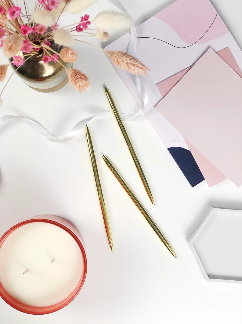 Candle, knitting needles, and stationery items on a light surface