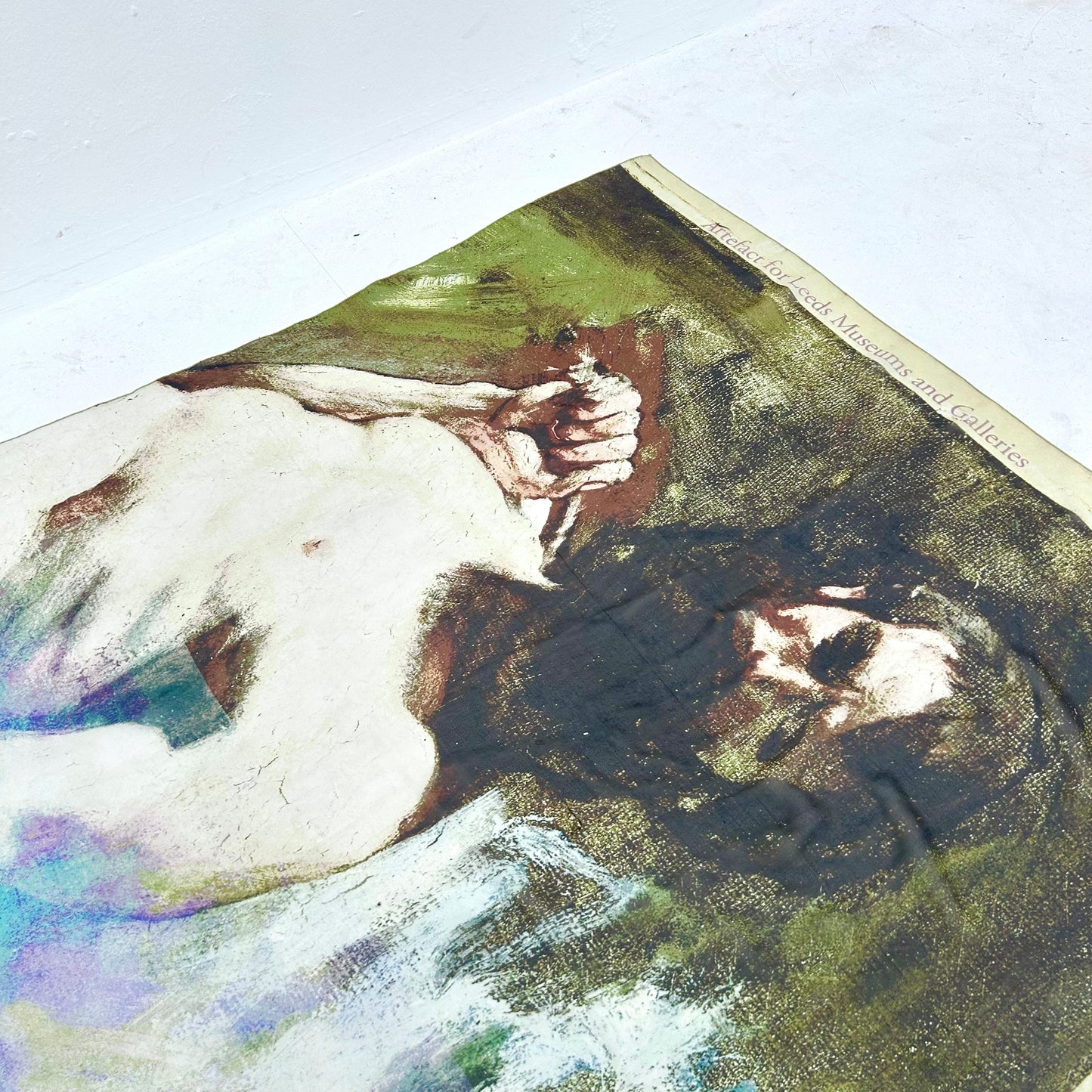 A scarf with a topless male on a green background, laid flat on a white surface.
