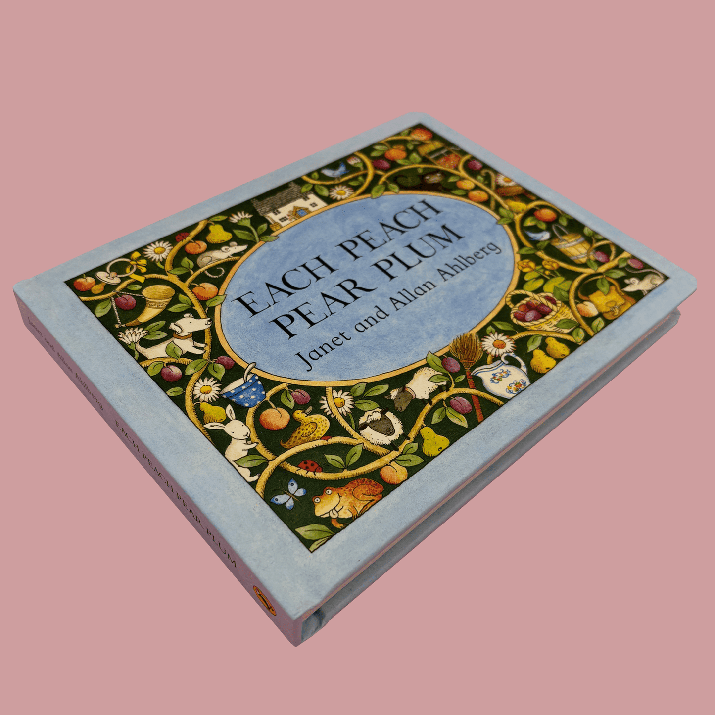 Book titled 'Each Peach Pear Plum' with decorative cover on a pink background