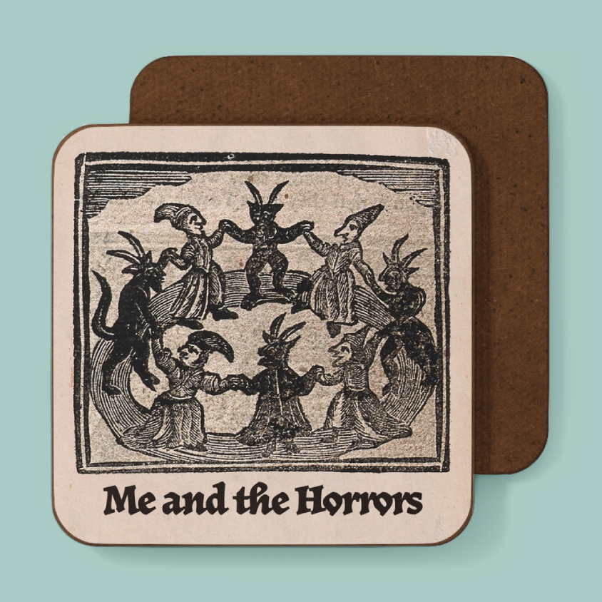 A square coaster with rounded corners featuring a vintage black-and-cream woodcut illustration of whimsical monsters and the text 'Me and the Horrors,' shown in front of a coaster with a brown back on a light aqua background.