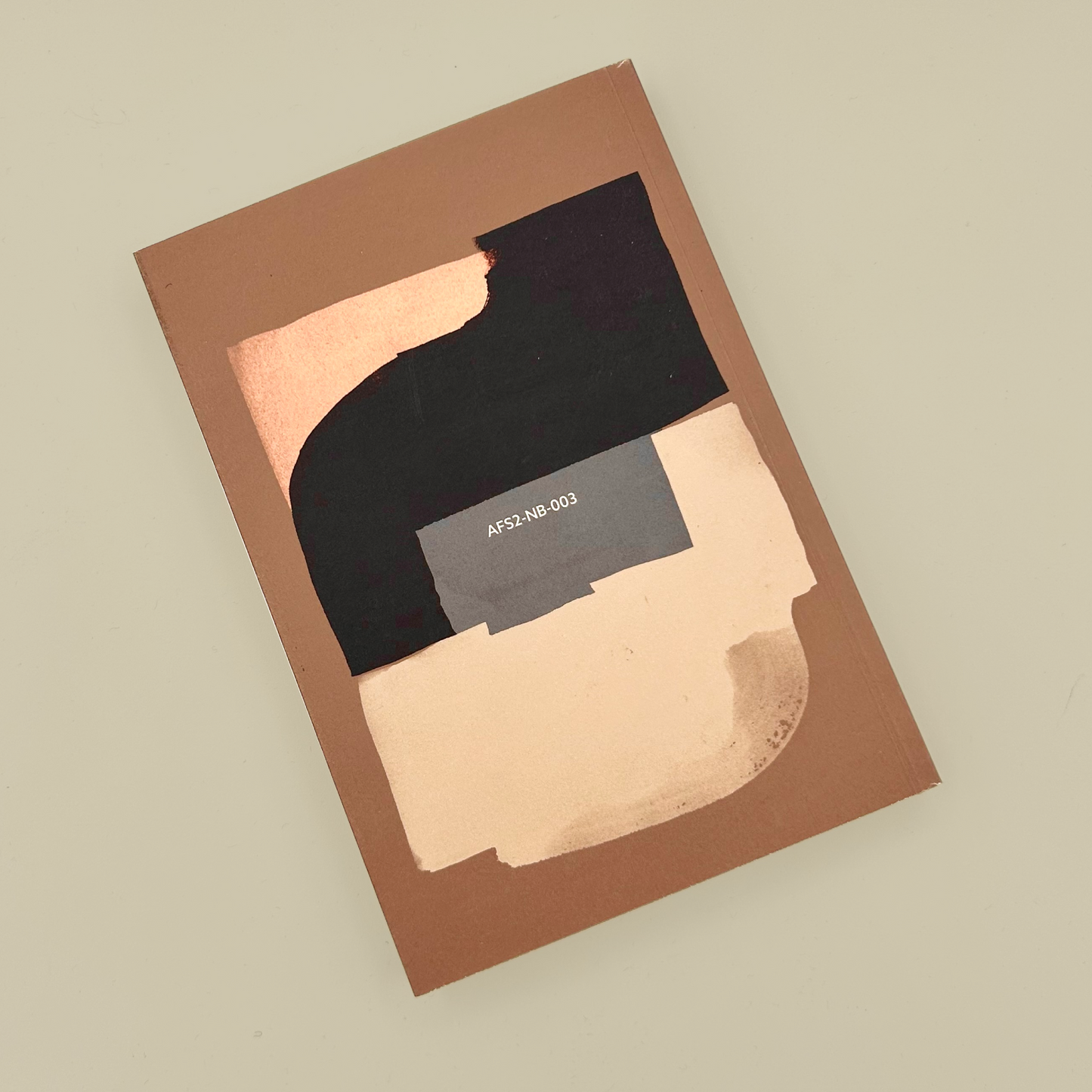 Back of a brown notebook with black and beige design on a beige background