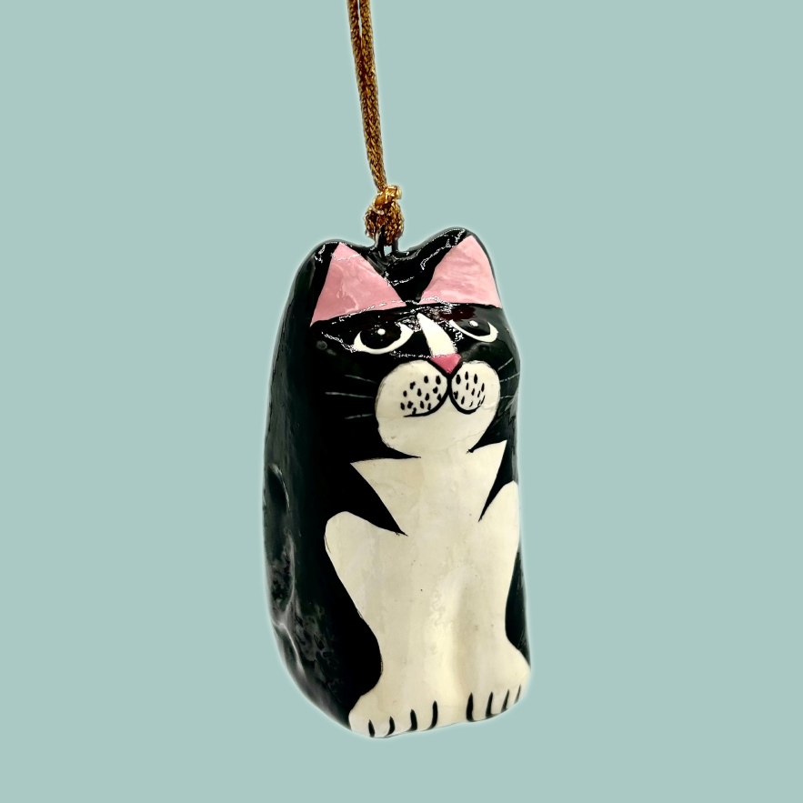 A cat shaped hanging decoration, painted in black and white and on a gold string.