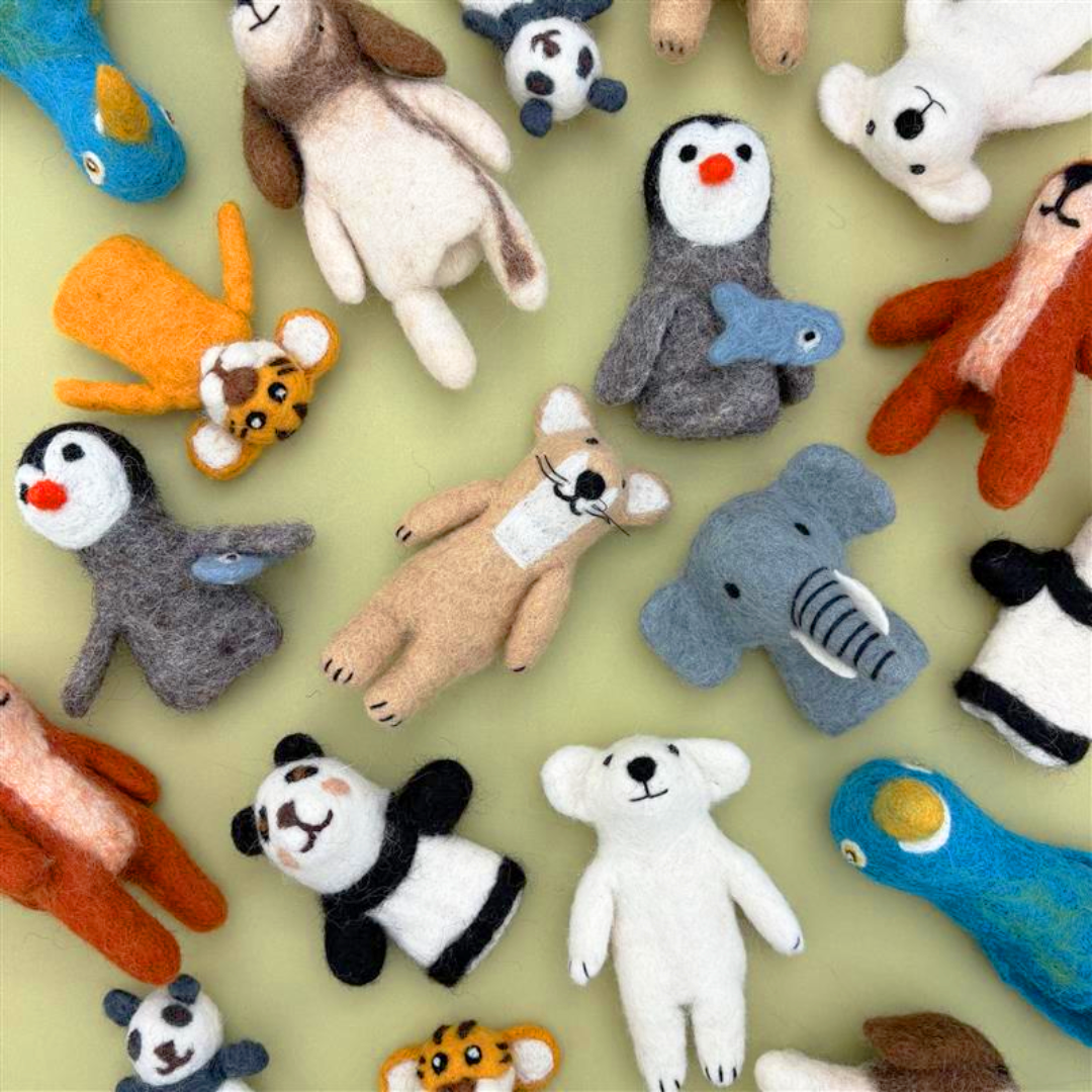 A flat lay image of a collection of felted finger puppets. The collection includes a panda, a parrot, a tiger, a dog, a fox, a polar bear, and a penguin.
