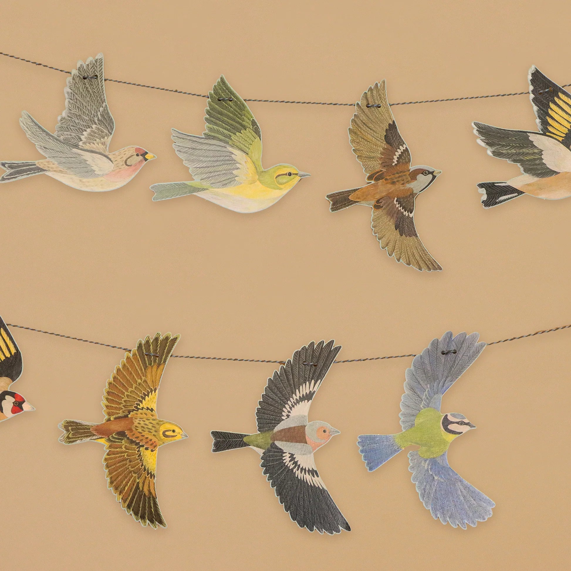 Decorations of various birds hanging on a string garland on a beige background