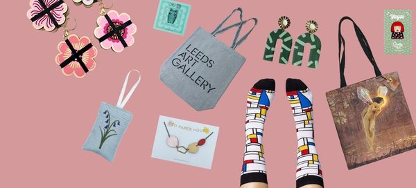 Collection of art-themed products including socks, bags, and cards on a pink background
