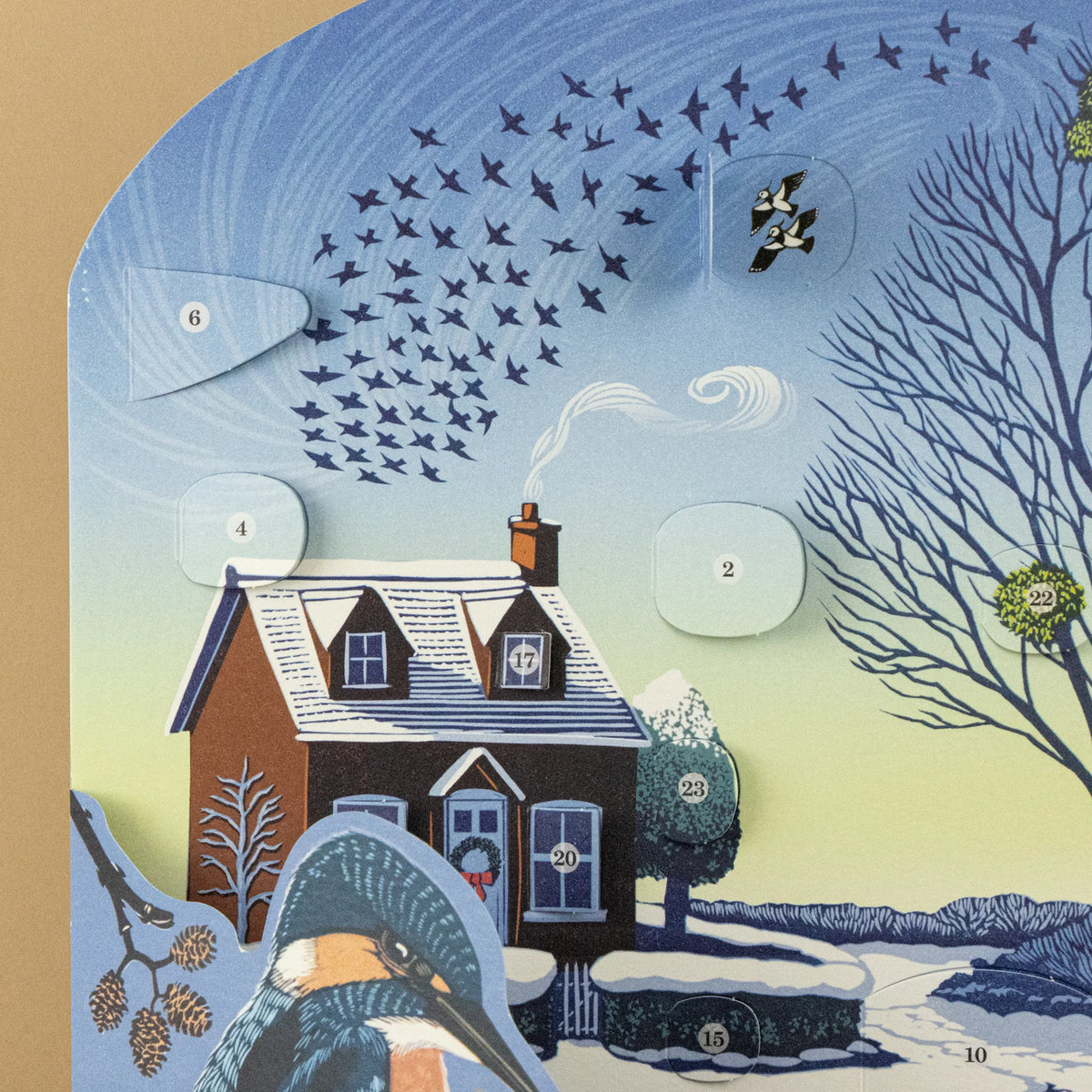 A winter-themed illustrated advent calendar showing a snow-covered house, flying birds, bare trees, and numbered cutout windows on a beige background.