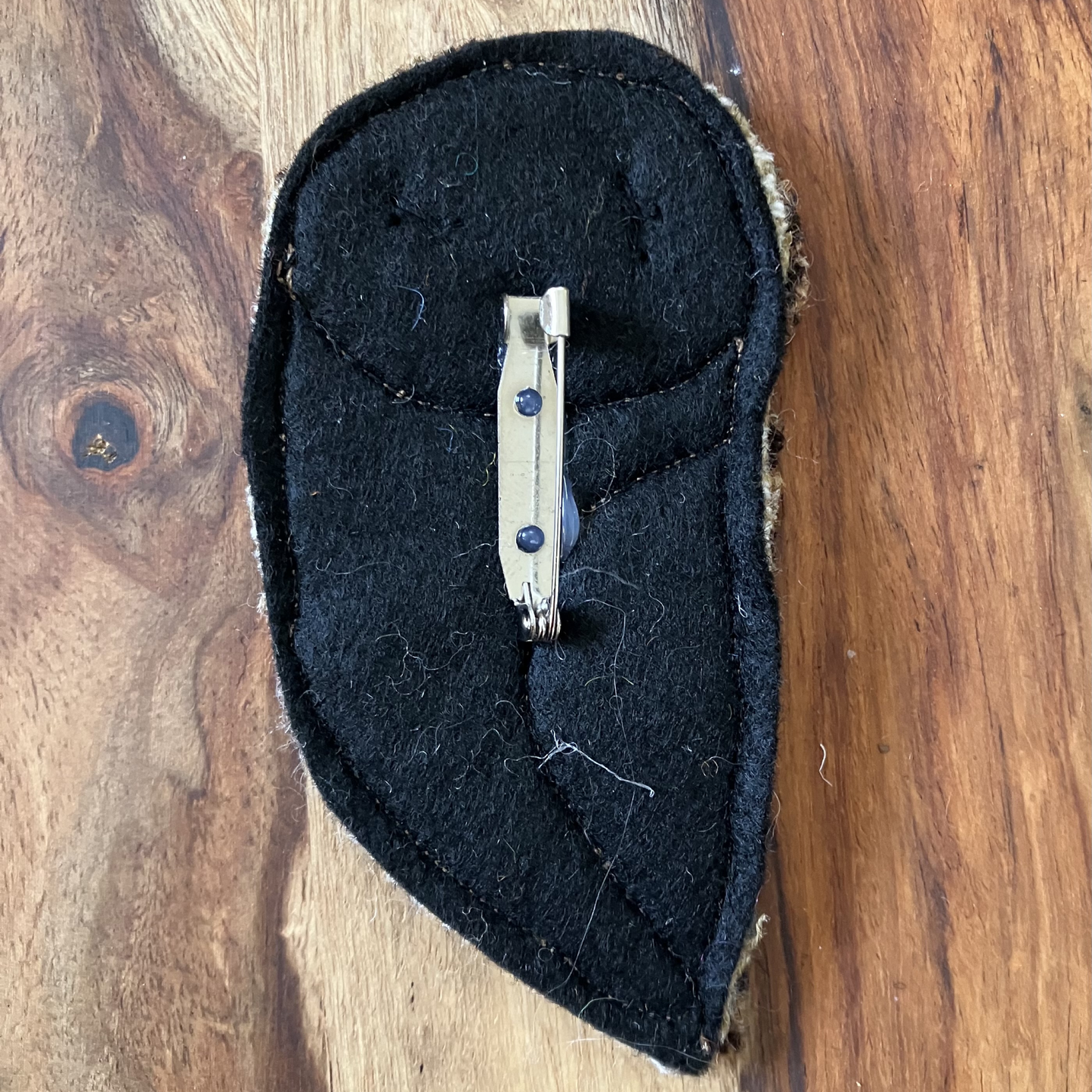 The back of a owl shaped badge showing the safety pin-style spring mechanism and clasp.