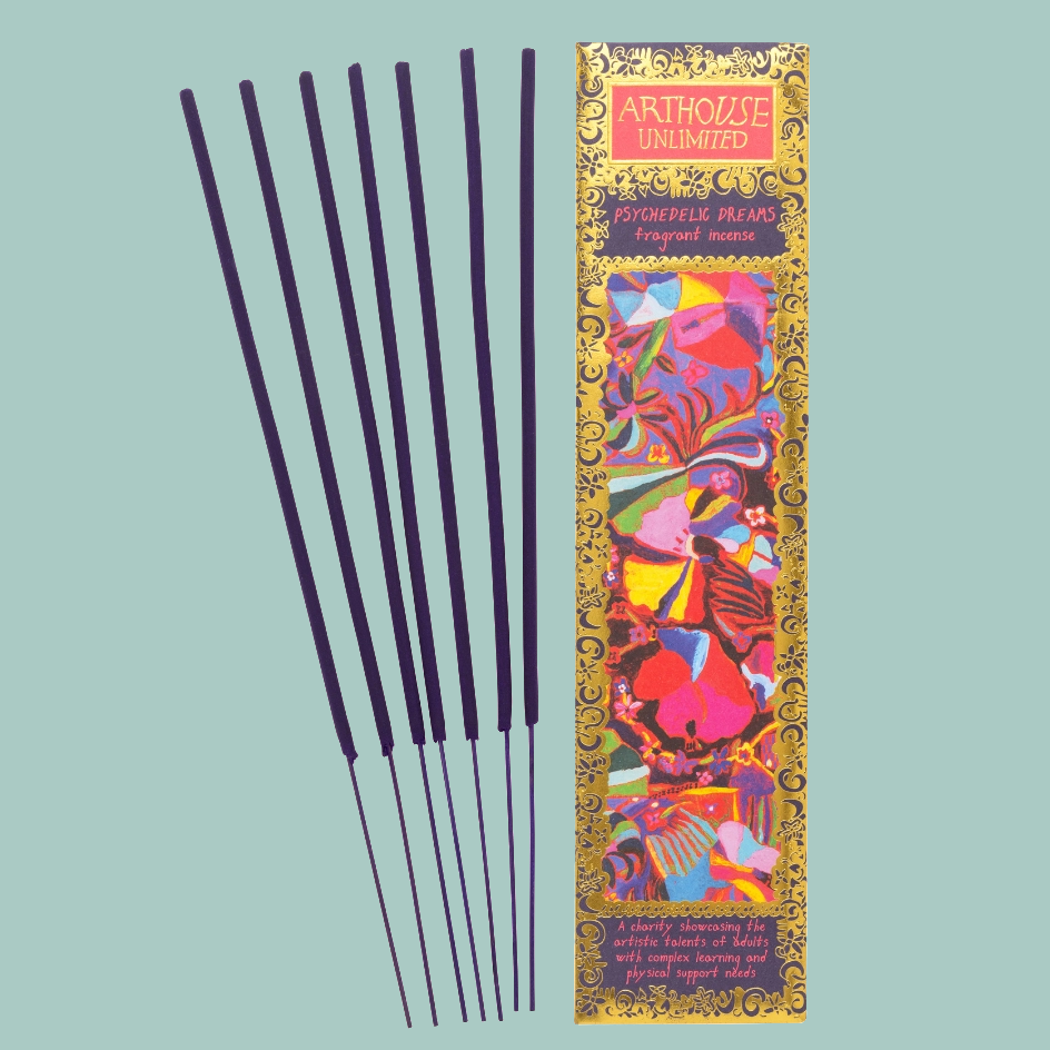 Six dark incense sticks are displayed next to their colorful packaging box on a solid light blue background. The box features a vibrant, multicolored abstract pattern with gold borders and the brand name 'ARTHOUSE UNLIMITED' at the top.