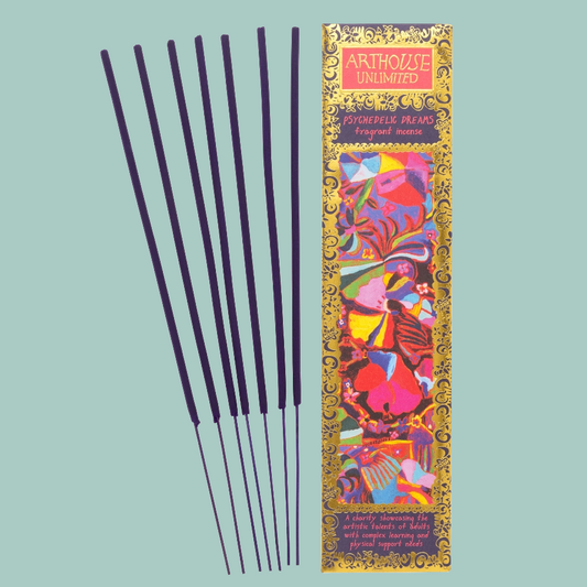 Six dark incense sticks are displayed next to their colorful packaging box on a solid light blue background. The box features a vibrant, multicolored abstract pattern with gold borders and the brand name 'ARTHOUSE UNLIMITED' at the top.