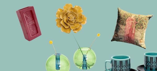 Collection of decorative items including a red bar, yellow flower, green vase with a blue candle, and a patterned pillow on a teal background.