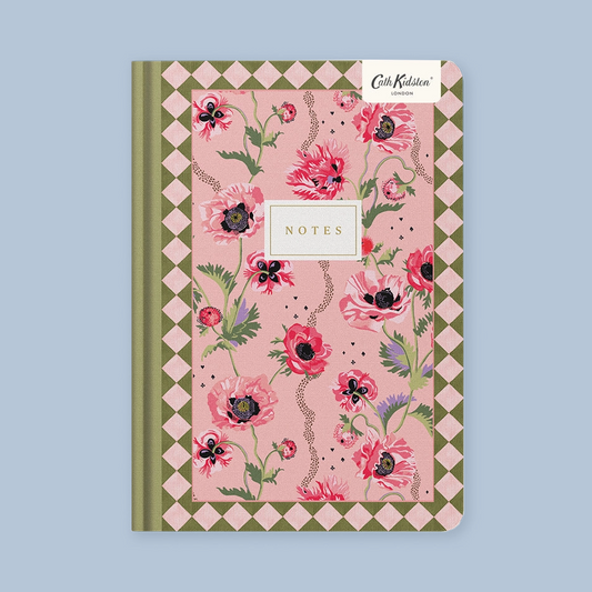 A pink floral patterned notebook with a green and pink diamond border, featuring a white 'Cath Kidston London' brand sticker and a central white 'NOTES' label, shown on a light blue background.