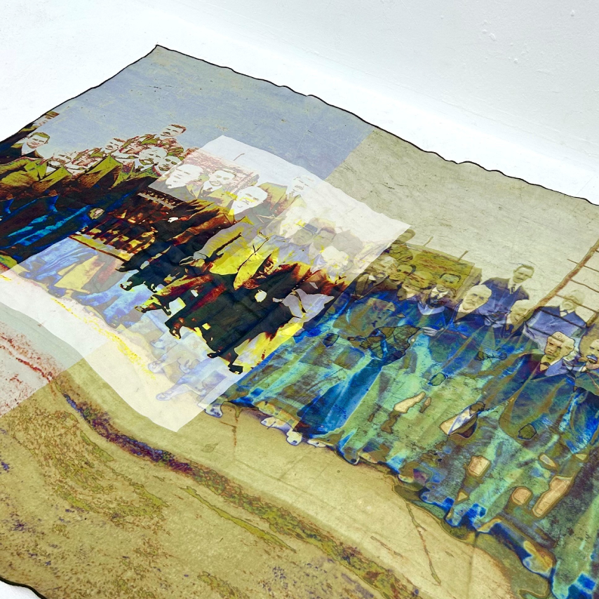 Silk scarf with printed photo of men on it, laid flat on a white background. 
