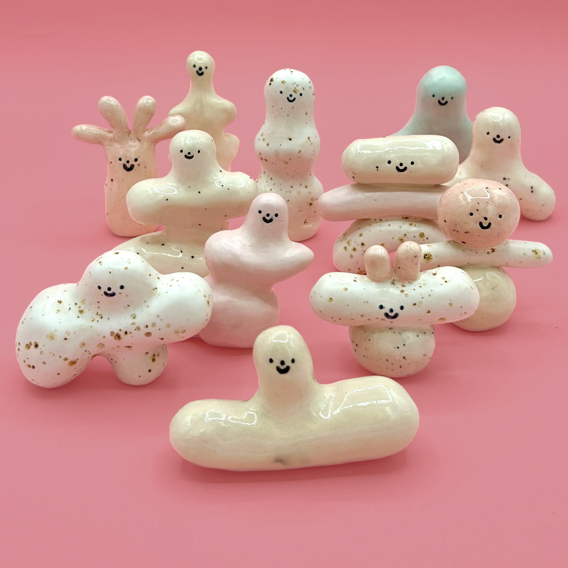 Set of white ceramic figures with smiling faces on a pink background