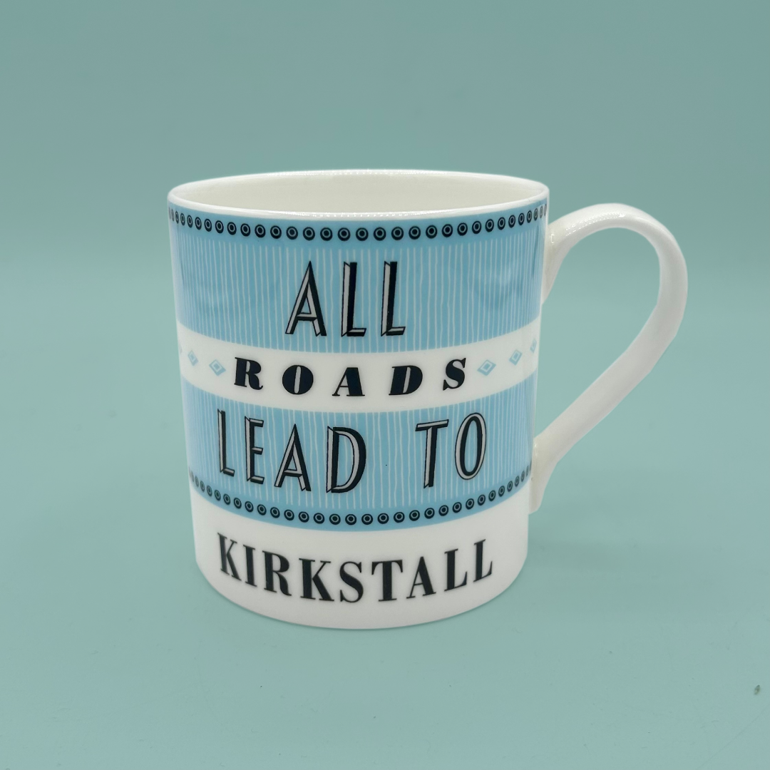 Mug with blue and white stripes and 'All Roads Lead to Kirkstall' text, on a teal background.