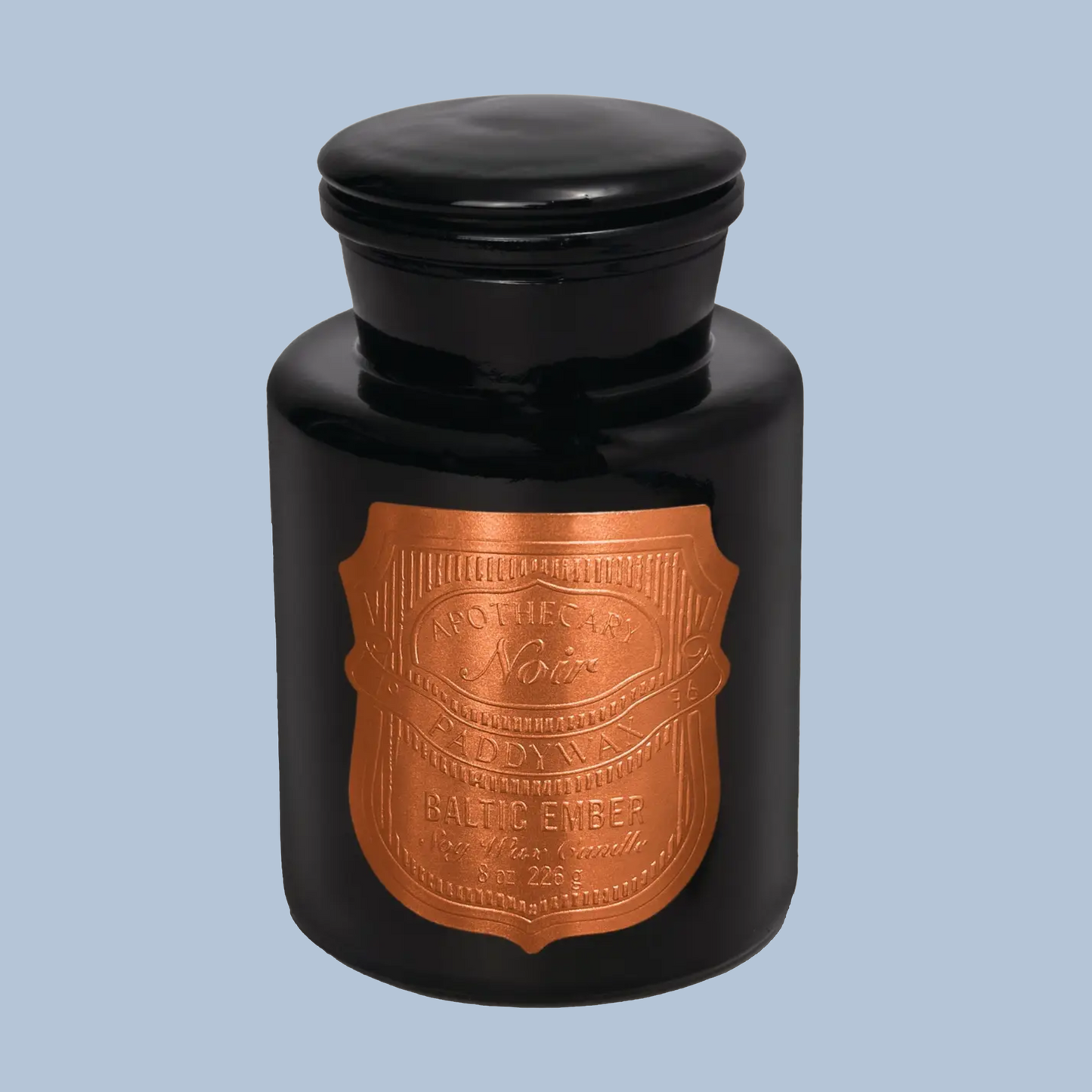 Black candle jar with a copper label on a light blue background
