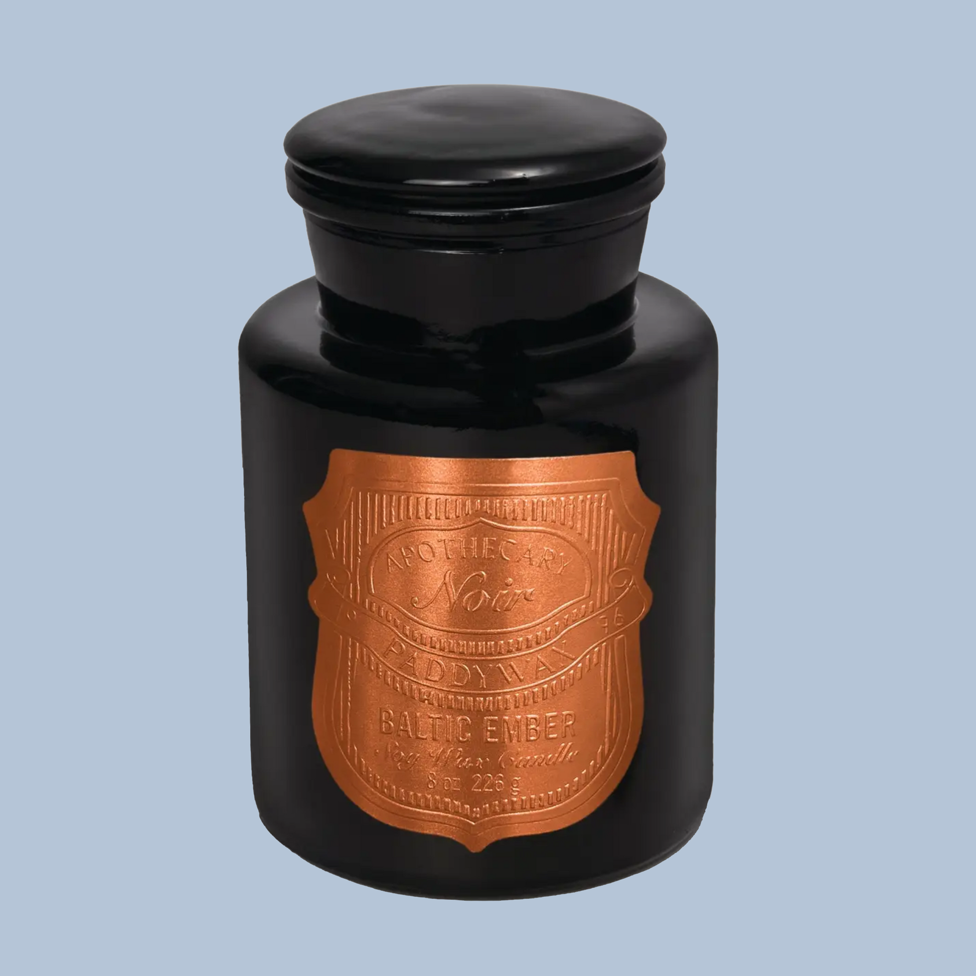 Black candle jar with a copper label on a light blue background