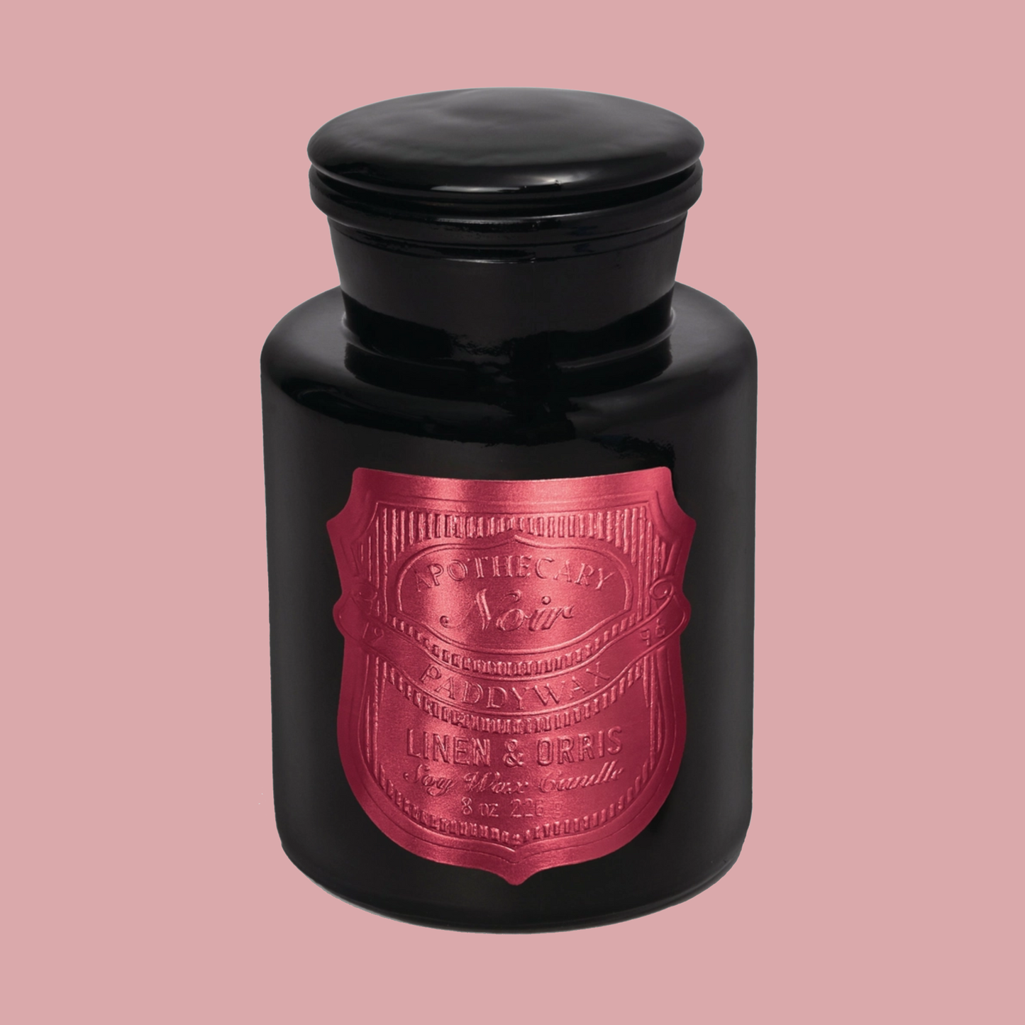 Black candle jar with a hot pink label on a pink background