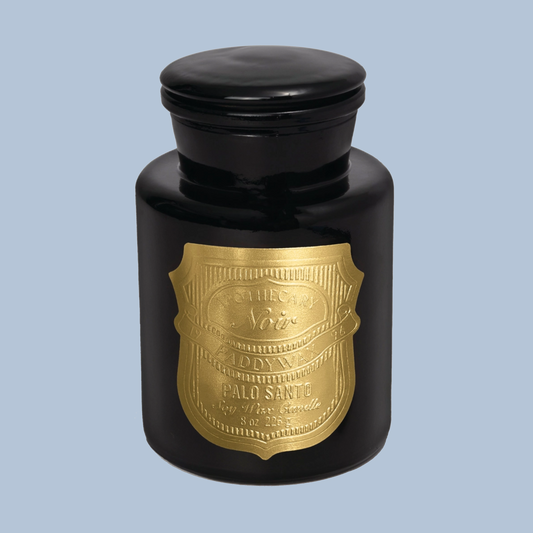 Black candle jar with gold label on a light blue background