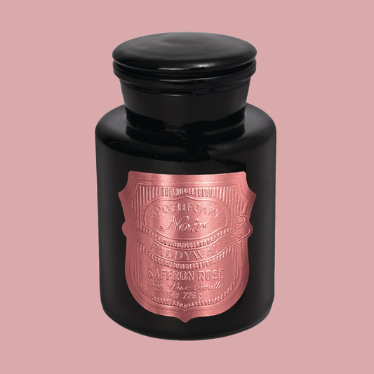 Black candle jar with a rose gold label on a pink background