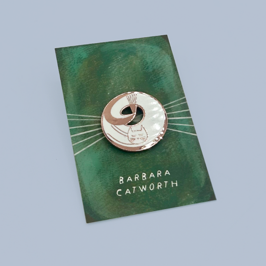 A circular enamel pin featuring a stylized cat illustration with the text 'BARBARA CATWORTH' on a green backing card, photographed on a light blue-gray background.