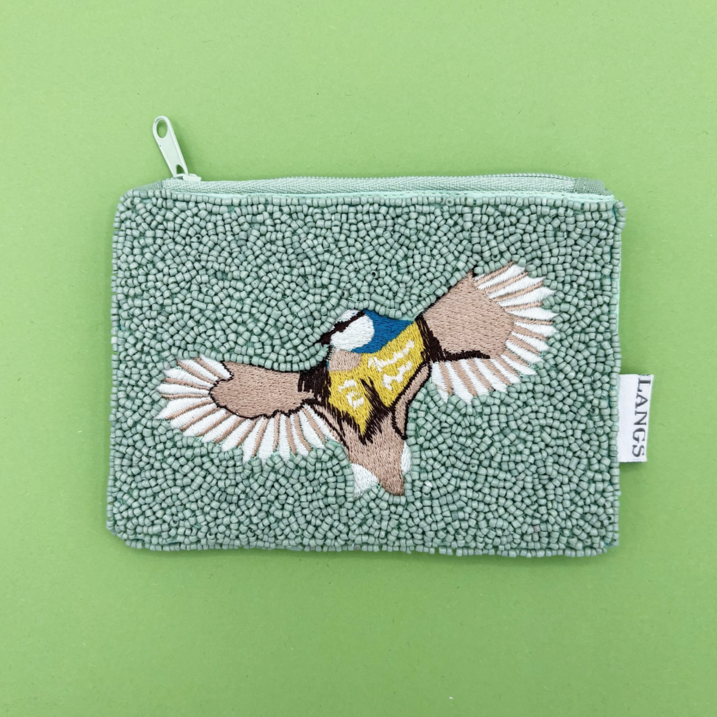 Textured pouch with embroidered bird design on a green background