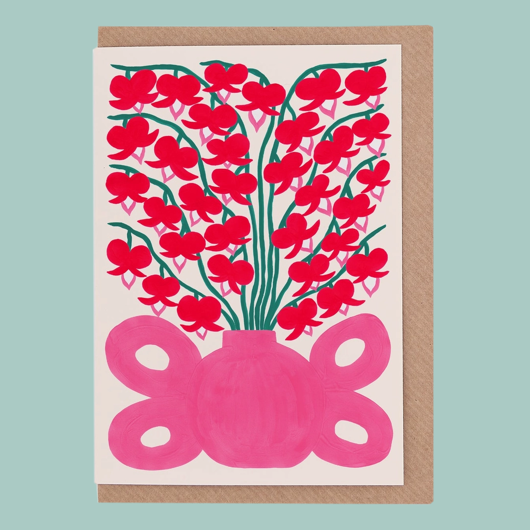 Greetings card with red floral design and pink vase on a light blue background.