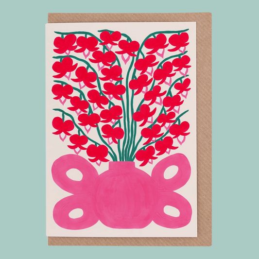 Greetings card with red floral design and pink vase on a light blue background.