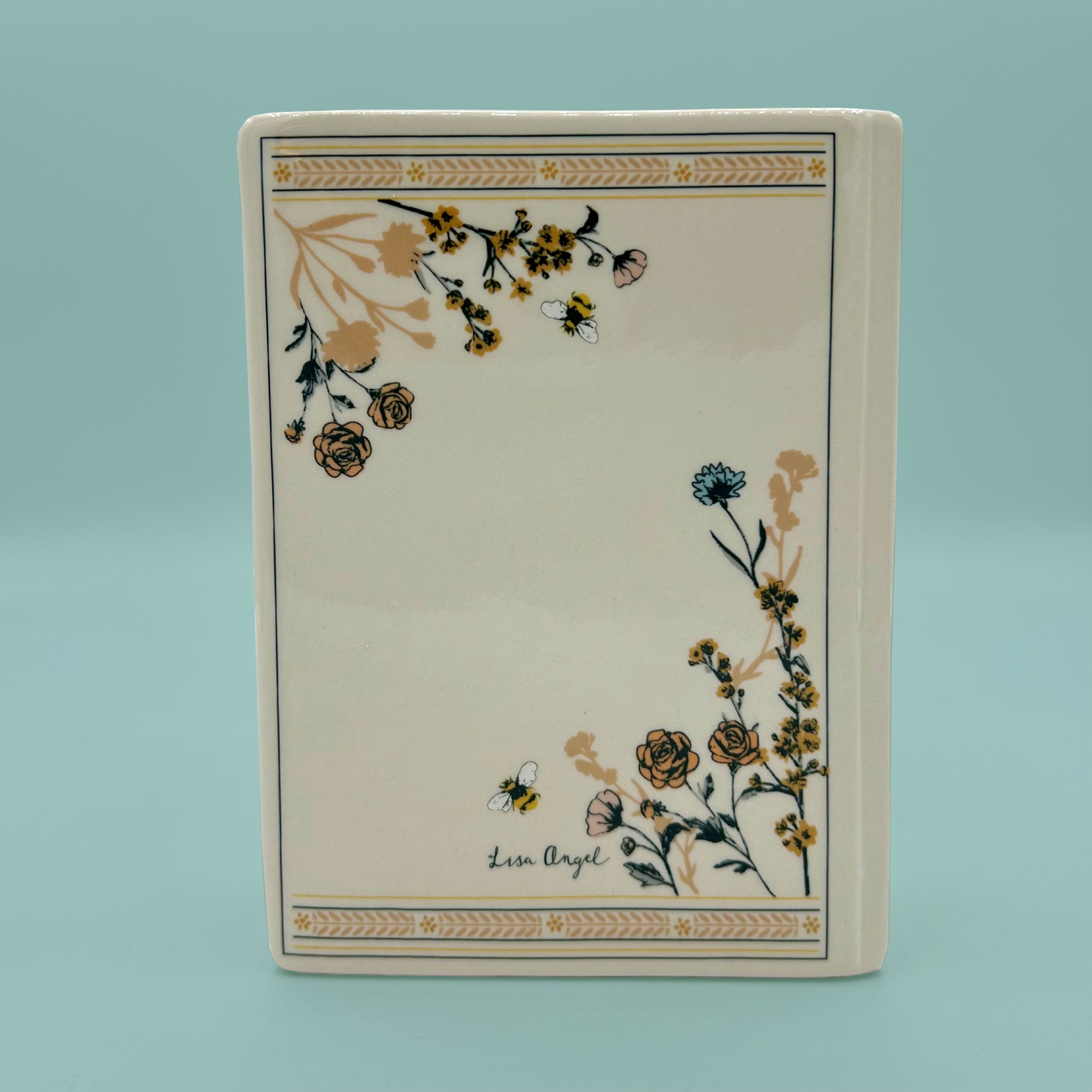 Back of a white book vase with floral designs and ornate embellishments. 
