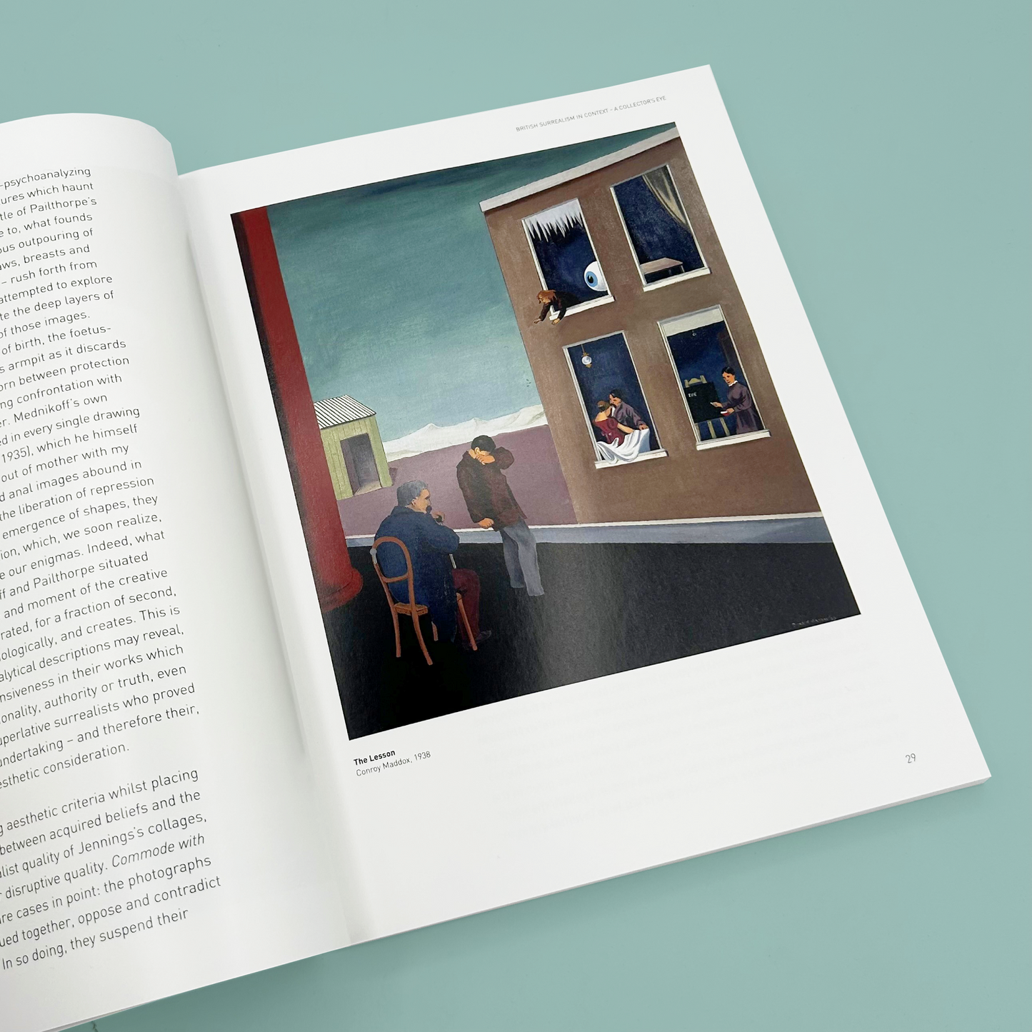 Open book with a painting of two people stood in front of an occupied building. 