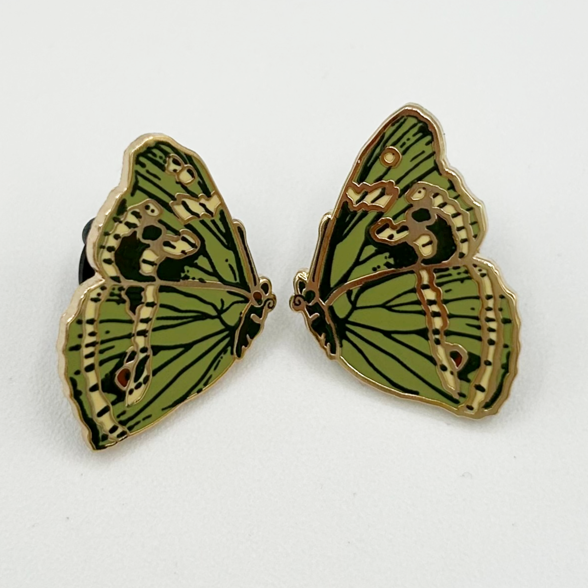 Green butterfly-shaped pin badges on a white background