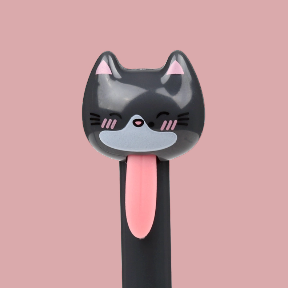 A novelty pen with a cartoon cat face on the top, featuring a black body, pink tongue, and pink inner ears, set against a solid pink background.