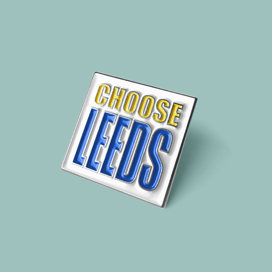 Enamel pin with 'CHOOSE LEEDS' text on a light blue background