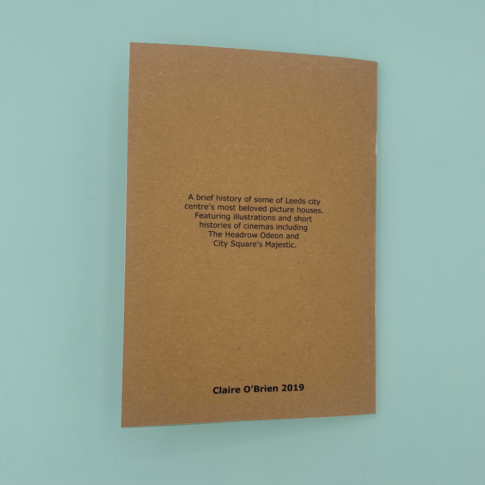 A  brown kraft-paper zine cover with black printed text, photographed against a light aqua background.