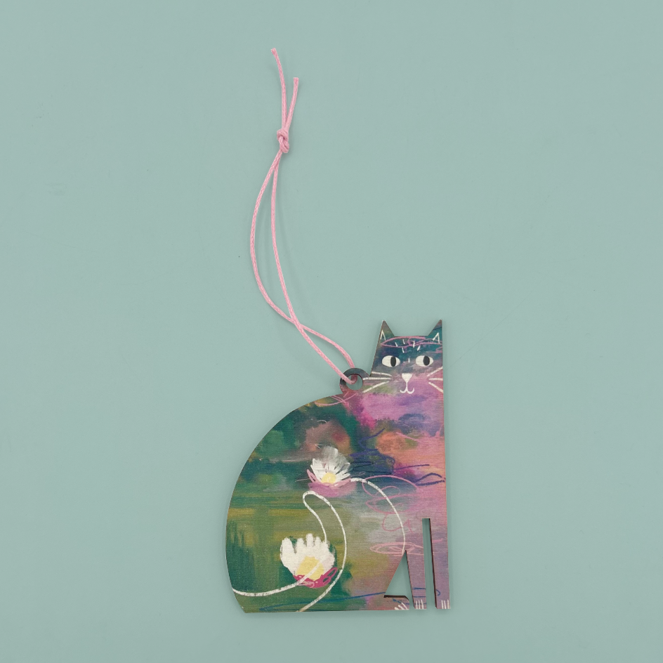 A cat shaped wooden hanging decoration with a pink string. The decoration is painted with water lillies in a watercolour style with green, purple, and blue. 