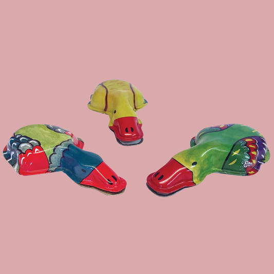 Colourful tin duck-shaped objects on a pink background