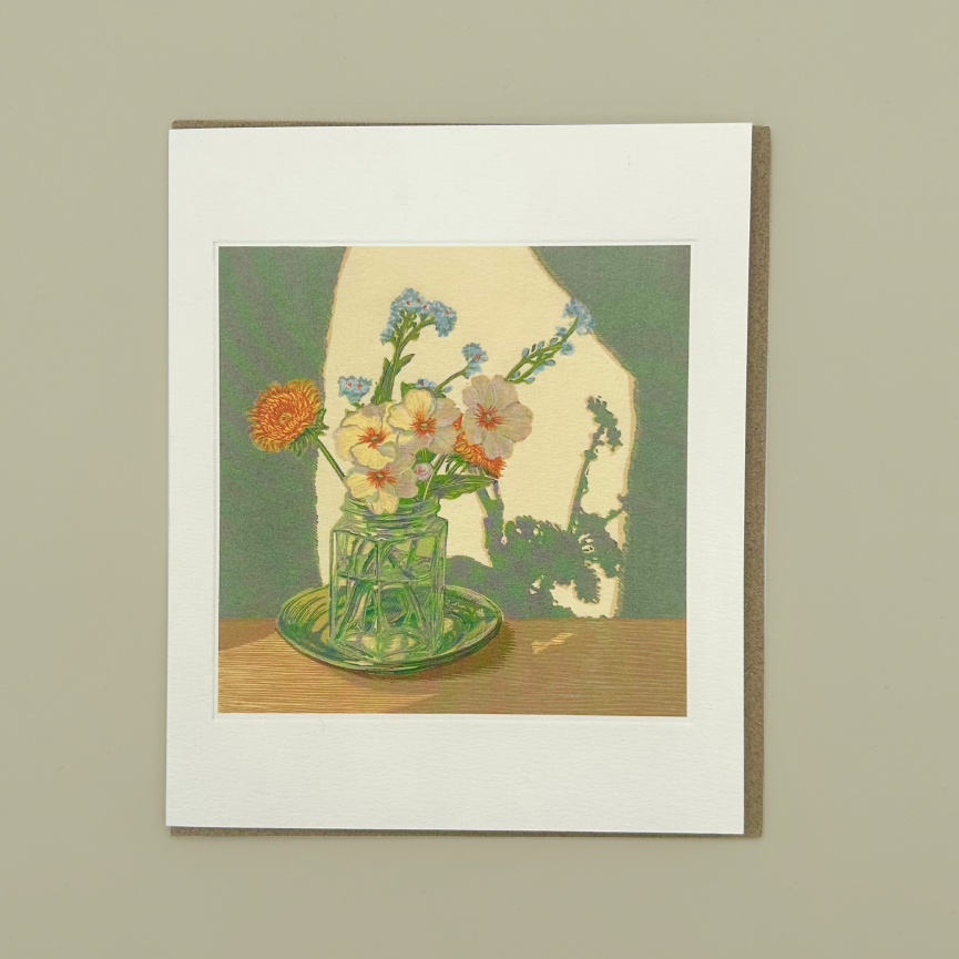 Greetings card of a still life with flowers in a glass jar on a wooden surface.