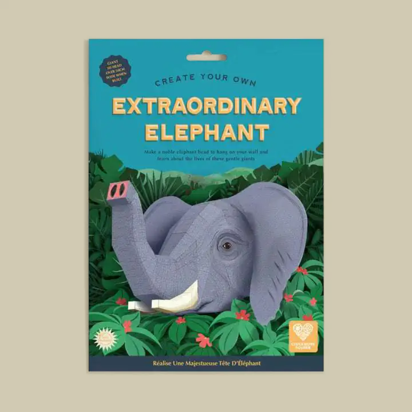 Packaged craft kit titled 'Create Your Own Extraordinary Elephant' showing a assembled gray elephant model on a tropical jungle-themed card backing, photographed against a plain beige background.