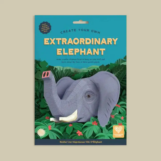 Packaged craft kit titled 'Create Your Own Extraordinary Elephant' showing a assembled gray elephant model on a tropical jungle-themed card backing, photographed against a plain beige background.