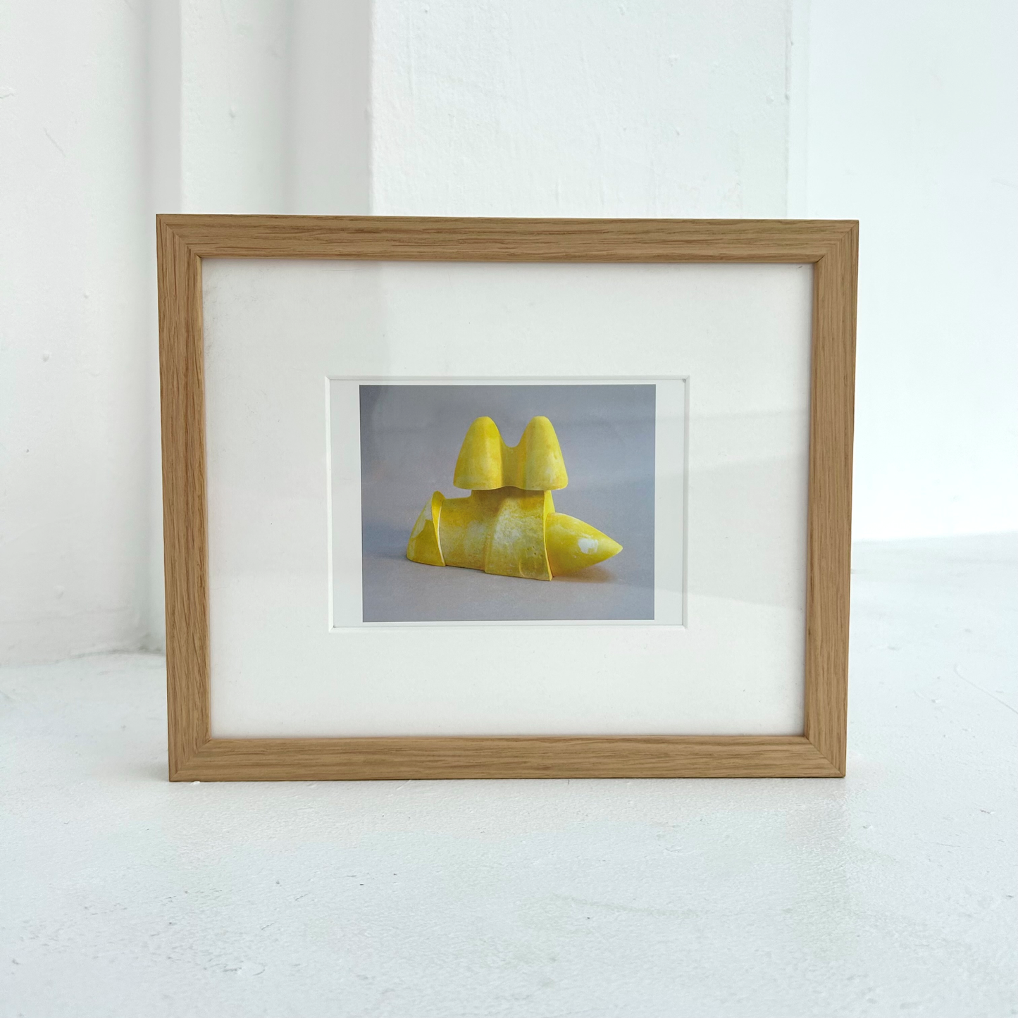 Framed picture of yellow sculpture on a white background.